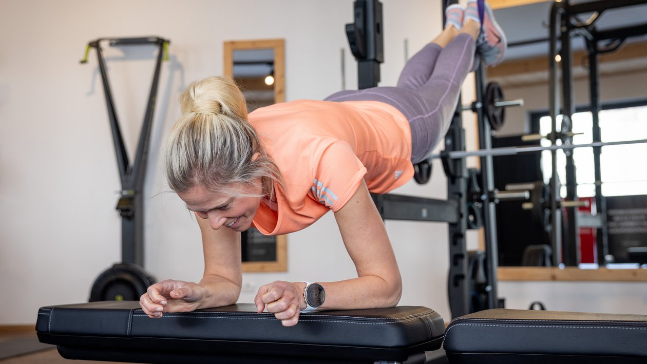 Stärkung mit Plank im Fitnessstudio Frau führt eine Plank-Übung auf einer Bank in einem Fitnessraum aus, konzentriert und stark.